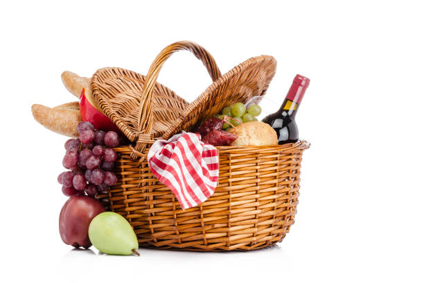Three quarters front view of a picnic basket shot on white background. Food usually taken for picnic like bread, grapes, cheese, a wine bottle and fruits are coming out of the basket. Useful copy space available for text and/or logo. High key DSRL studio photo taken with Canon EOS 5D Mk II and Canon EF 100mm f/2.8L Macro IS USM.