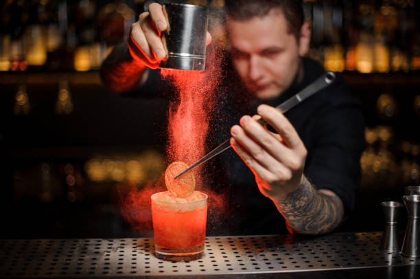 istock Professional barman adding to an alcoholic cocktail a dried orange and powder 1134311010