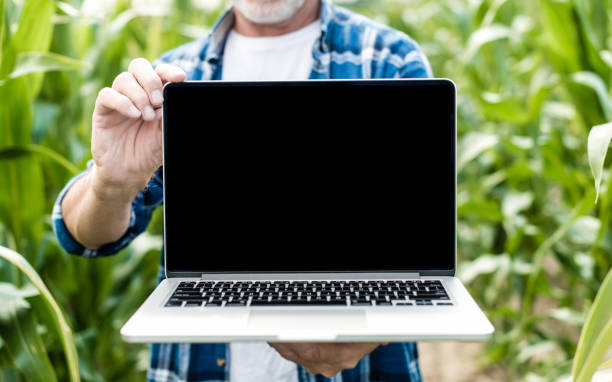 granjero en el campo mostrando la pantalla del ordenador portátil, foto de cierre - farmer rural scene laptop computer fotografías e imágenes de stock