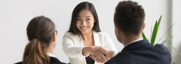 Photo of Smiling asian female vacancy candidate shaking hand with hr manager