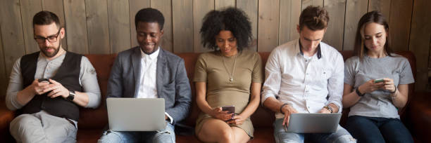 istock Five diverse businesspeople girls guys sitting on couch using gadgets 1134312176