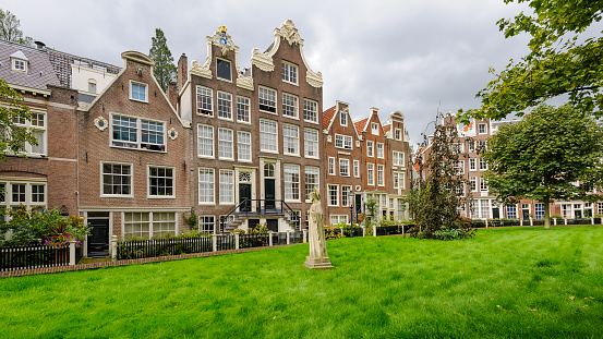A sunny view of the Begijnhof (Béguines court), a beautiful medieval inner court in the city center of Amsterdam, Netherlands.