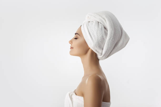 Beautiful young woman after bath on white background Spa skin care beauty woman wearing hair towel after beauty treatment. Beautiful multiracial young woman with perfect skin isolated on white background. Mixed race Caucasian Asian with closed eyes. Side view. Copy space background woman wrapped in bath towel stock pictures, royalty-free photos & images