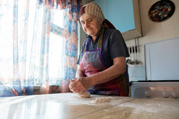 starsza kobieta ugniata ciasto w kuchni domowej, babcia gotuje wypieki, świeży chleb, smaczne ciasto - grandmother pie cooking baking zdjęcia i obrazy z banku zdjęć