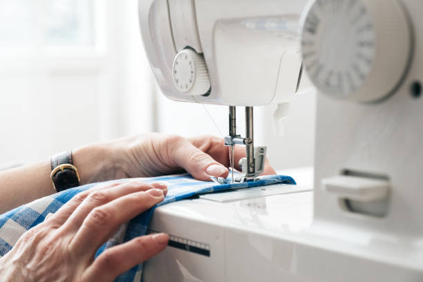 Hands of a woman using a sewing machine in tailor workshop. Hands of a woman using a sewing machine in tailor workshop. atelier fashion photos stock pictures, royalty-free photos & images