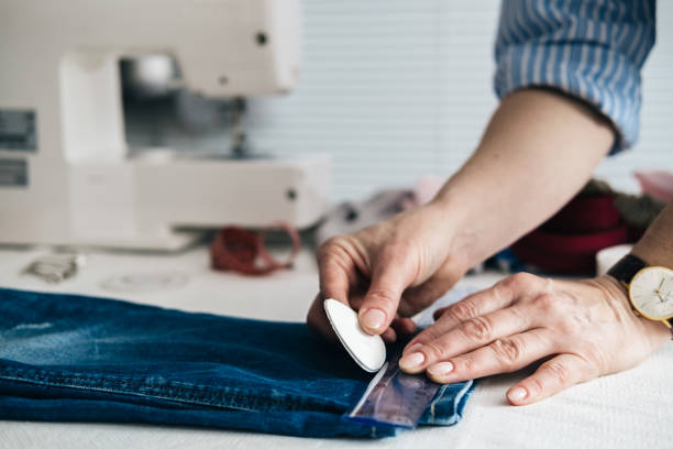 seamstress marking hem on a pair of jeans in tailor shop - textile sewing women part of imagens e fotografias de stock