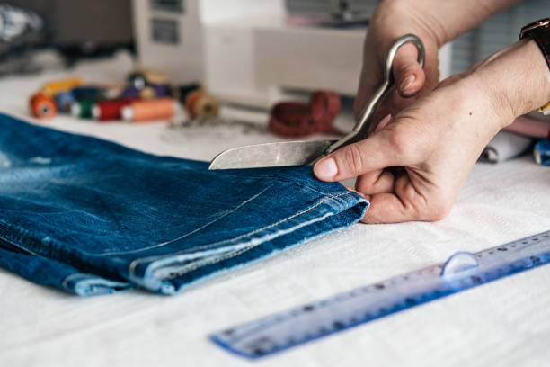 maßgeschneiderte schnärzungsjeans mit schere in der werkstatt - schneiderberuf stock-fotos und bilder