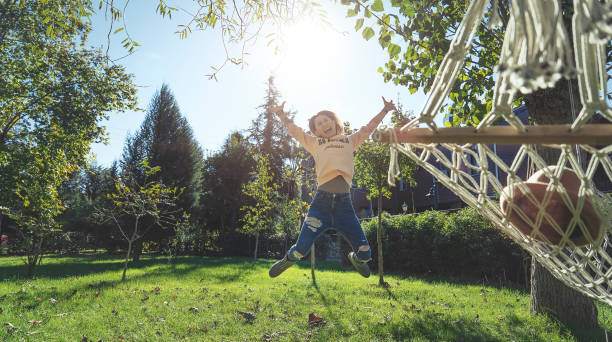 happy woman jumping in woods - back lit - back lit women one person spring imagens e fotografias de stock