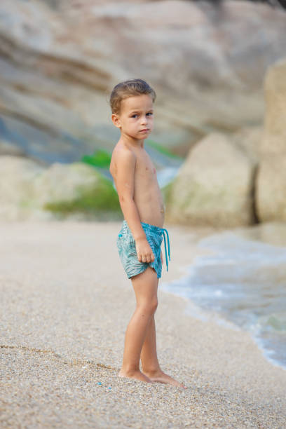 istock boy standing on the sand by the sea 1134330985