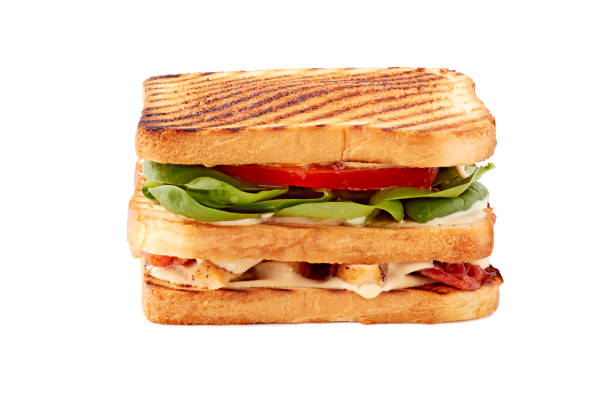 On the plate are two triangular-shaped sandwiches. One sandwich of white bread, the other of dark. Filling of tuna sandwiches, hard boiled eggs and vegetables. Light background. Close-up.
