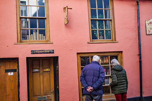 March 4 2019 - Cromer, Norfolk, England: Unidentified married couple of pensioner age browsing the window display of a book shop in the coastal town of Cromer
