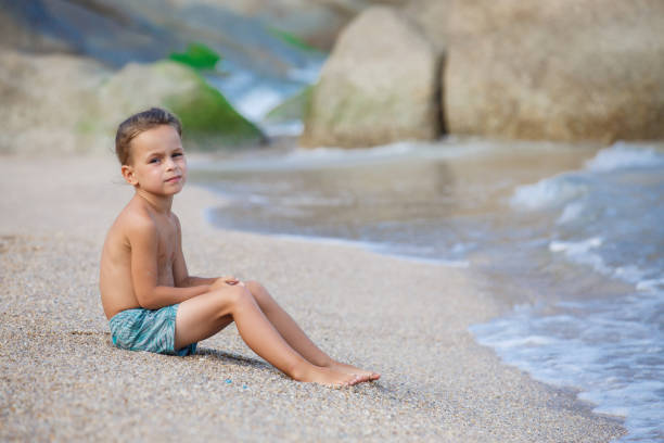 istock boy sitting on the sand by the sea 1134332912