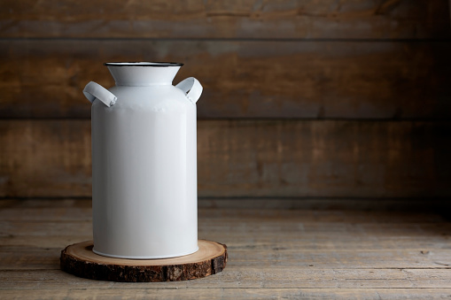 White metal milk jug on a wooden background. Mockup is ready for your design or logo to be added.
