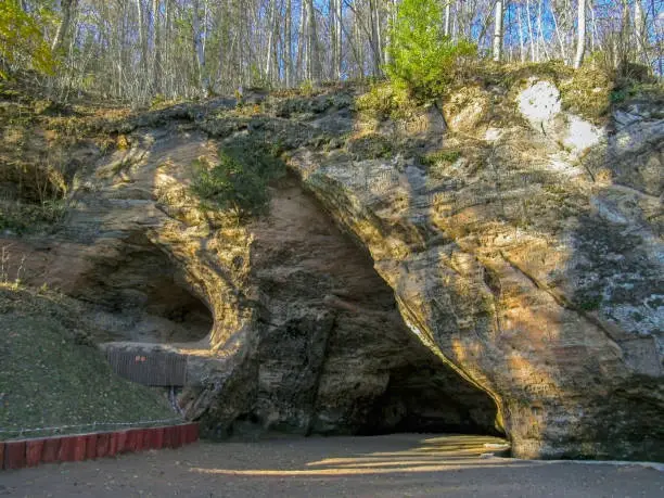 Photo of Gutmanala yellow sandstone cave with inscriptions, biggest grotto in Baltics, Gauja National Park, Sigulda, Latvia