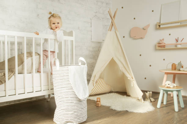 retrato lindo bebé niña de pie en la cuna en su cuarto de niños - teepee fotografías e imágenes de stock