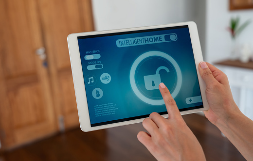 Close-up on a woman using a tablet computer to control her intelligent home â technology concepts. **DESIGN ON SCREEN WAS MADE FROM SCRATCH BY US**