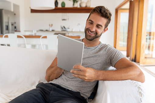 Portrait of a happy Brazilian man at home using a tablet computer and smiling â lifestyle concepts