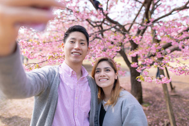 istock Multi-ethnic couple taking selfie picture in front of cherry blossoms 1134350406
