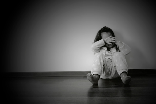 sad little girl sitting on the floor in black and white background