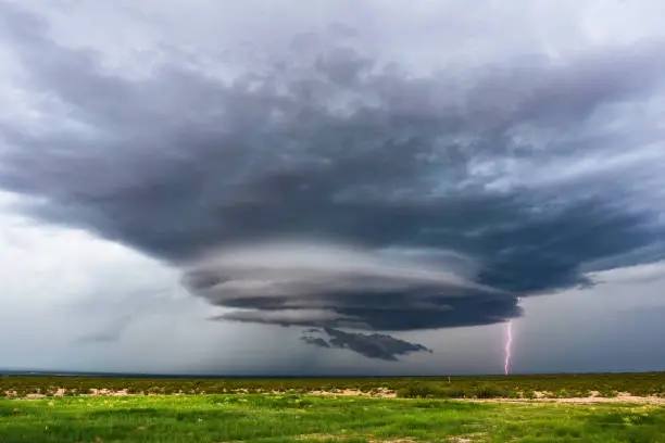 Supercell thunderstorm with dramatic, dark clouds with lightning bolt.