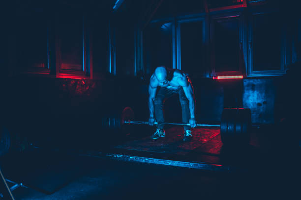 Handsome, muscular athlete is deadlifting at the gym.