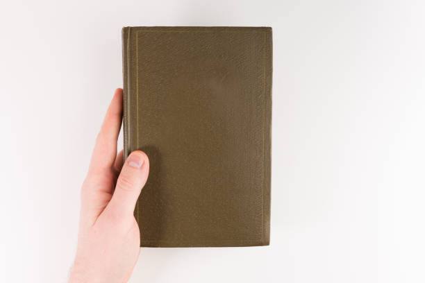 istock Overhead view of hands holding a blank closed book, isolated on white background 1134364092