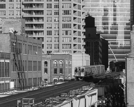 An elevated train above Lake Street in the West Loop neighborhood. Main streets in Chicago, streets in Illinois, public transportation. Black and white.