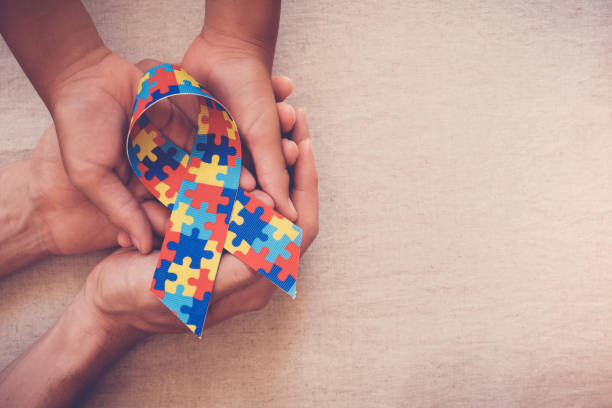 mains retenant le ruban de puzzle pour la sensibilisation d'autisme - social awareness symbol photos photos et images de collection