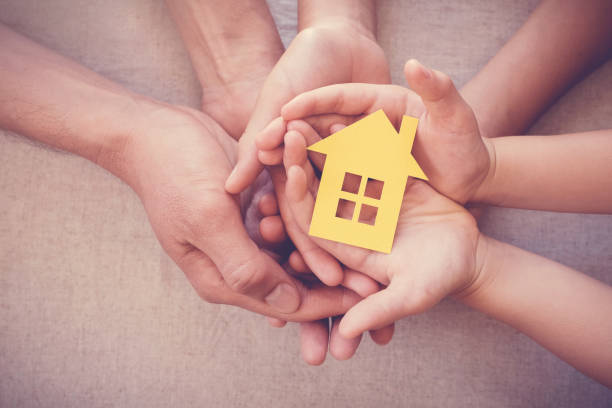 黄色の家、家庭やホームレスの避難所の概念を保持している大人と子供の手 - social insurance ストックフォトと画像