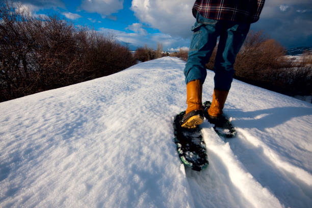 The legs, boots and snowshoes of a man snowshoeing along a trail near Council, Idaho.
