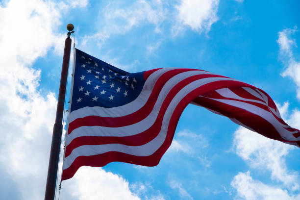 istock American Flag Against Cloudy Blue Sky 1134371501