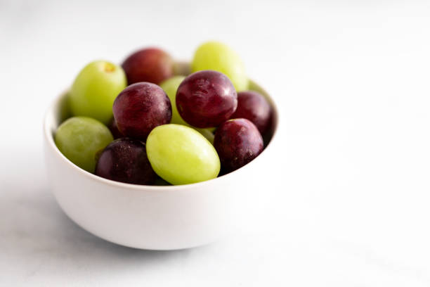 Bunch of red grapes and white grapes inside a fruit bowl ready to eat.