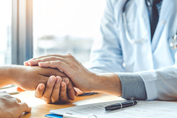 Doctor holding hands for comforting and care patient stock photo