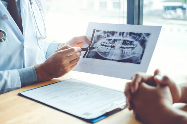 Dentist talking to male patient and presenting results on Dental x-ray film About the problem of the patient in dental office stock photo
