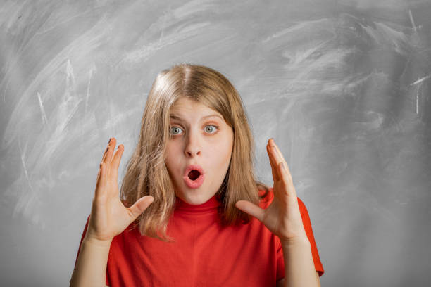 Blonde girl looking surprised into camera portrait in studio
