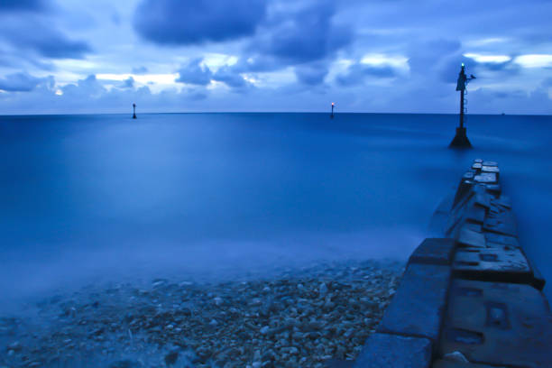 A long exposure shot of a blue sunset with beacon and stone formations