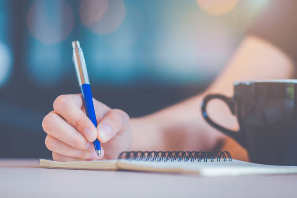 istock Business woman's hand is writing on a notebook with a pen. 1134386252