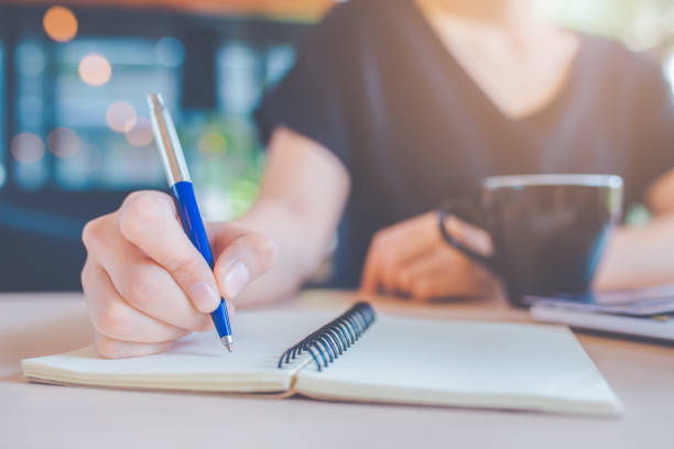 istock Business woman hand is writing on a notebook with a pen. 1134386256