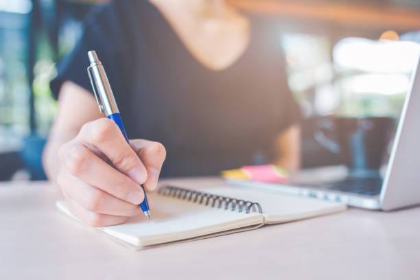 istock Business woman's hand is writing on a notebook with a pen. 1134386257