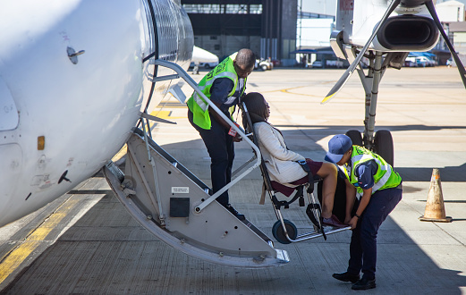Johannesburg, South Africa, 28th February - 2019: Disabled passenger being helped to board aircraft with help from ground crew