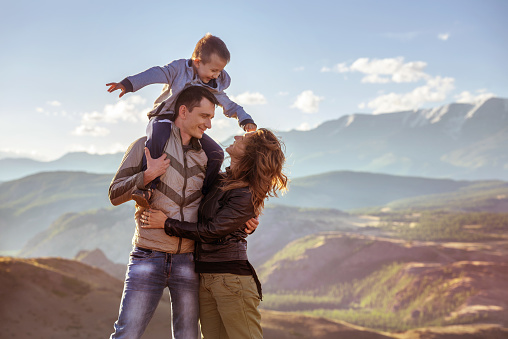 Happy family with young son stands against mountains
