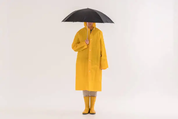 Middle adult woman in yellow raincoat and rain boots