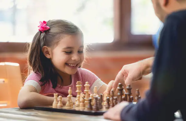 Photo of Father Teaching His Daughter to Play Chess At Home