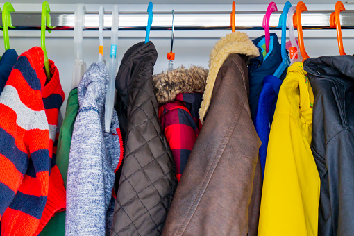 Chaquetas de niño pequeño tamaño, abrigos y suéteres colgando en el armario de un niño con perchas de colores. photo