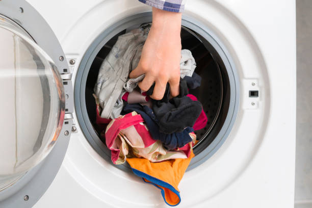 istock persons hand put dirty clothes in the washing machine b 1134415434