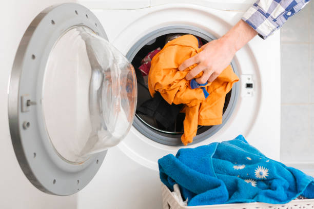 istock persons hand put dirty clothes in the washing machine b 1134415439