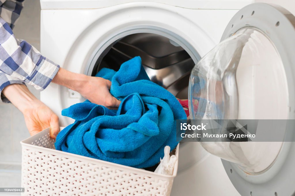 persons hand put dirty clothes in the washing machine b persons hand put dirty clothes in the washing machine Washing Machine Stock Photo