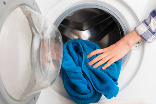 istock persons hand put dirty clothes in the washing machine b 1134415443