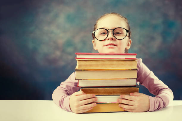 istock Cute Elementary Schoolgirl Hold Book Bunch at Desk. Toned 1134418037