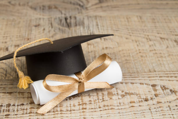 education concept. Graduation hat with gold tassel, scroll on the on a wooden table. Law concep- with copy space for your ad text. stock photo